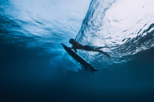 Surfista hombre con tabla de surf buceo bajo el agua de la gran ola del océano
. - Foto, imagen
