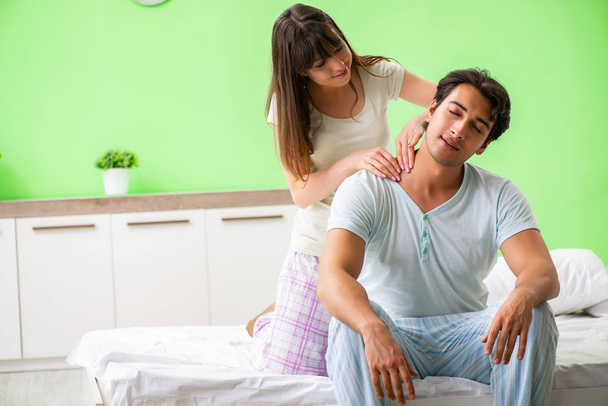 Woman doing massage to her husband in bedroom  - Foto, imagen