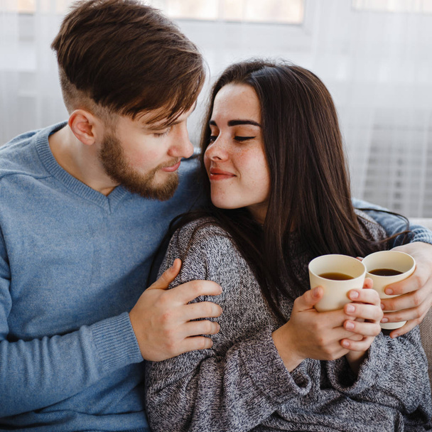 Young man and woman cuddling, drinking coffee - Fotoğraf, Görsel