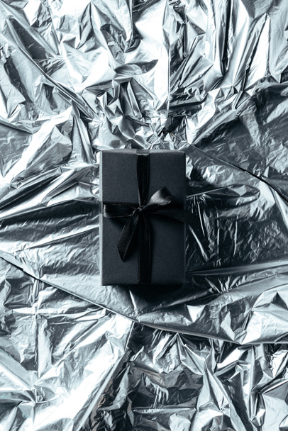 top view of gift box with black ribbon on silver wrapping paper backdrop - Zdjęcie, obraz