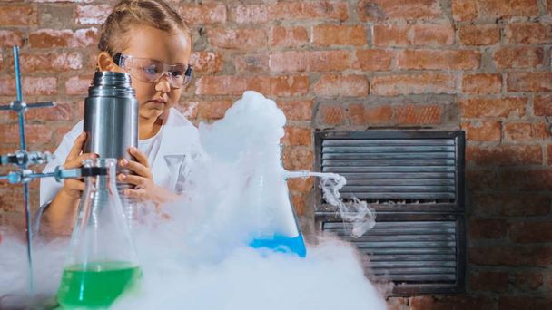 Cute child researcher is conducting an experiment with liquid nitrogen - 写真・画像