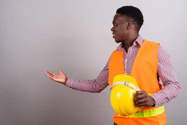 Young African man construction worker showing something against  - Фото, зображення