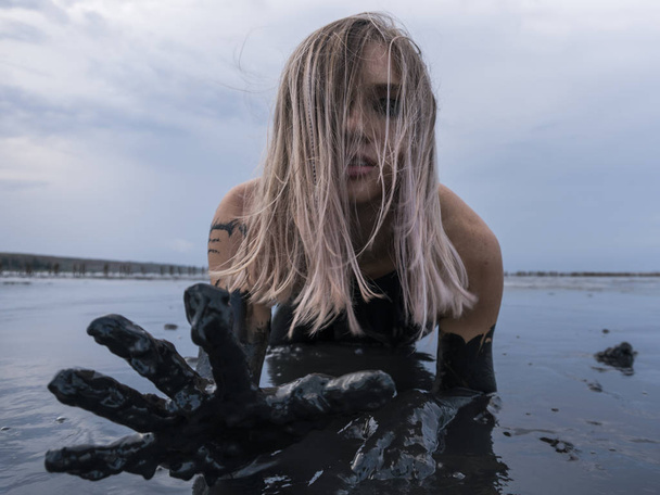 main tendue de blonde caucasienne fille rampe enduit dans une boue noire en bonne santé dans le vieux Firth
 - Photo, image