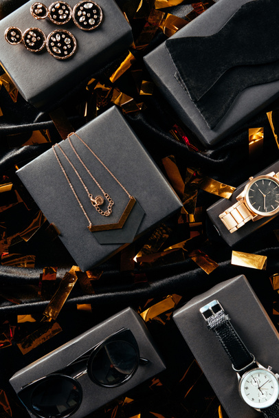 Układ płaski z kobiece buty, torebki i biżuteria na czarnym tle z złotym konfetti  - Zdjęcie, obraz