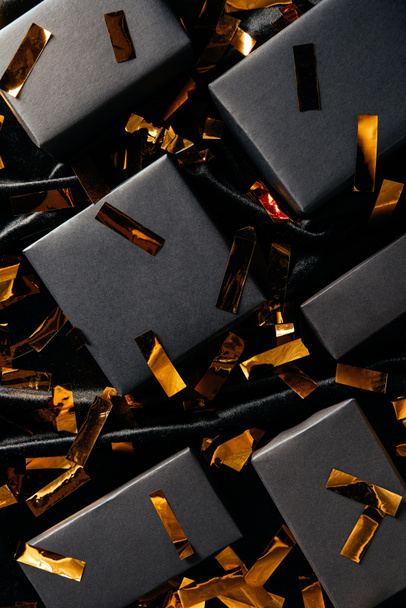 flat lay with boxes and golden confetti on black backdrop, black friday concept - Foto, Imagen
