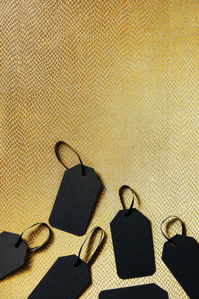 top view of black blank price tags on golden backdrop, black friday concept - Fotografie, Obrázek