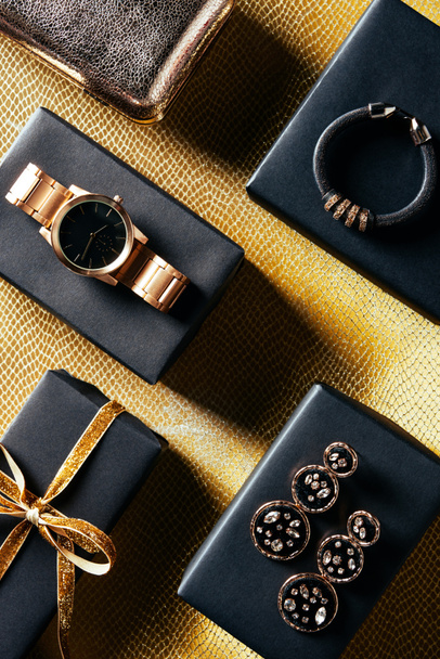 flat lay with wrapped gift, feminine jewelry and purse on golden backdrop - Photo, Image