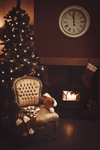 Véspera de Natal com cadeira rugindo fogo e meias de Natal e chapéu de Santa
 - Foto, Imagem