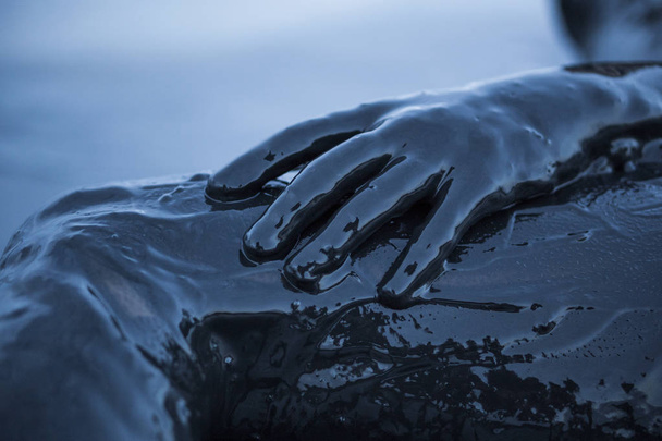 Close-up van de hand van een meisje in een zwarte modder van een gezonde zout Kuyalnik Firth in Odessa, Oekraïne Smeared. - Foto, afbeelding