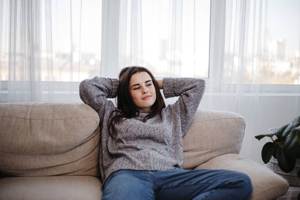 Young woman relaxing on a couch in living room - Foto, afbeelding