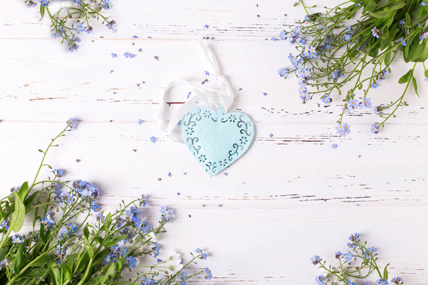 Decorative heart and blue myosotis flowers on white background.  - Foto, imagen