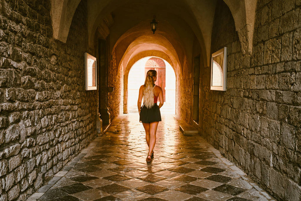 Tourist woman walking across medieval stone tunnel - Zdjęcie, obraz
