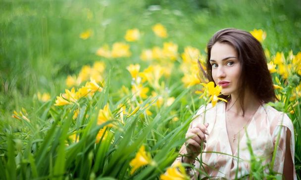 若い柔らかい黄色の花春の野でポーズ シフォンのドレスを着た女性  - 写真・画像