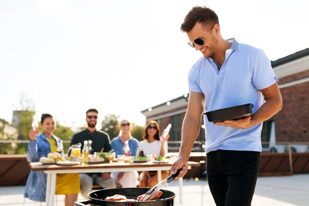 man cooking meat on bbq at rooftop party - Photo, image