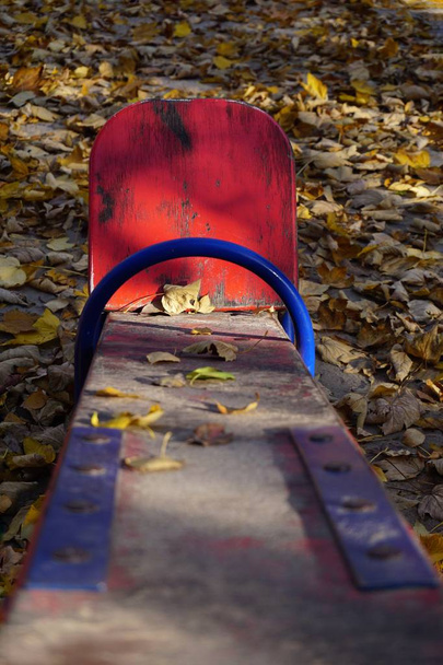 Дитячий майданчик з червоною хусткою для двох дітей. Стара пілінгова фарба, сонячно-золота осінь
.  - Фото, зображення