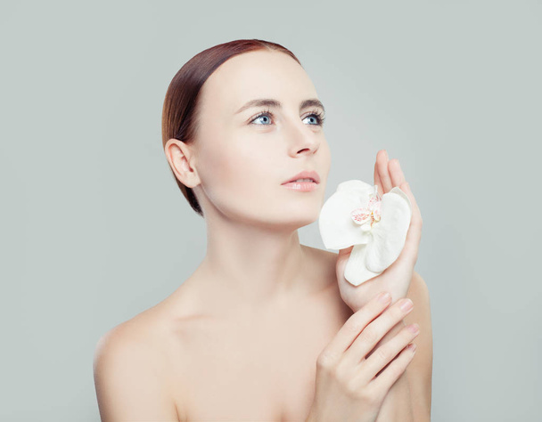 Młoda kobieta z zdrowej skóry i kwiat, patrząc na białym tle. Spa beauty, Kosmetologia, zabieg na twarz i koncepcji odnowy biologicznej  - Zdjęcie, obraz