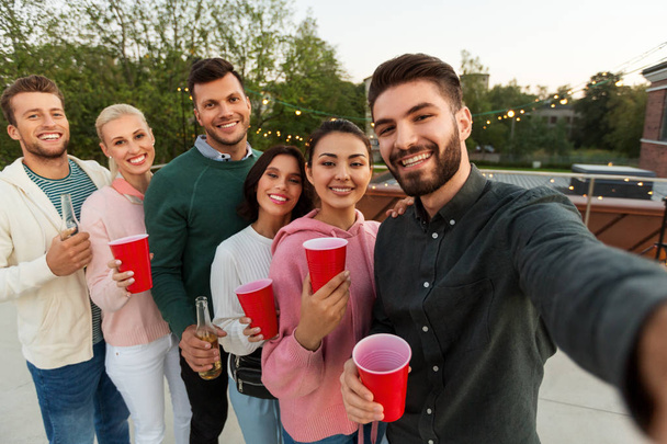 friends with drinks taking selfie at rooftop party - Фото, изображение
