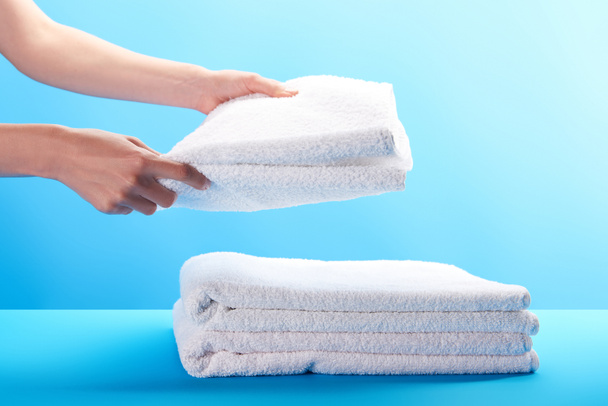 cropped shot of person stacking clean white towels on blue  - Photo, image