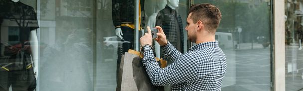 Man taking a photo of a shop window of a fashion store - Φωτογραφία, εικόνα