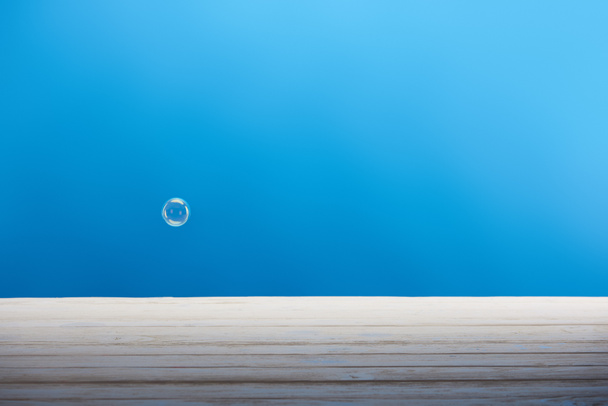 bolla di sapone e superficie in legno bianco su sfondo blu
 - Foto, immagini