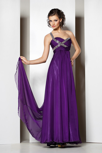 Young beautiful brunette in purple dress on white - 写真・画像