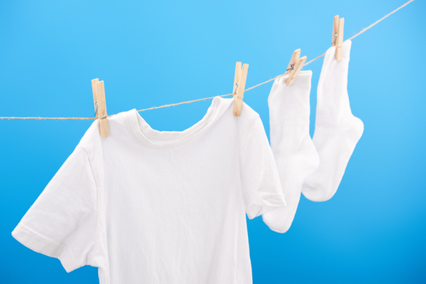 chaussettes blanches propres et t-shirt suspendu sur corde à linge isolé sur bleu
 - Photo, image