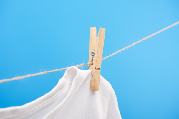 close-up view of clean white t-shirt with clothespin hanging on rope isolated on blue  - Foto, Imagem