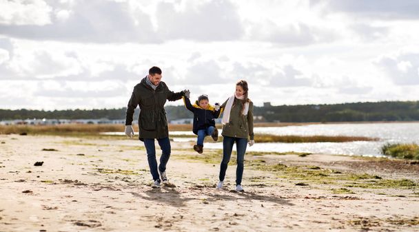 秋のビーチに沿って歩いて幸せな家族 - 写真・画像