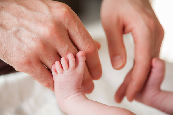Руки отца касаются ног новорожденного
 - Фото, изображение