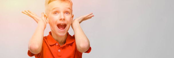retrato de pouco loira surpreso caucasiano feliz sorrindo menino no laranja t-shirt enganando no cinza fundo
 - Foto, Imagem