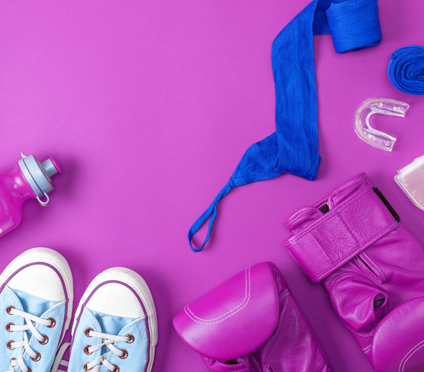  pair of leather pink boxing gloves, a blue textile bandage and a water bottle on a pink background, empty space, abstract sports background - Photo, Image