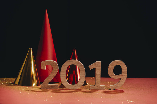 wooden numbers 2019 with colorful christams paper hats on background - Photo, image