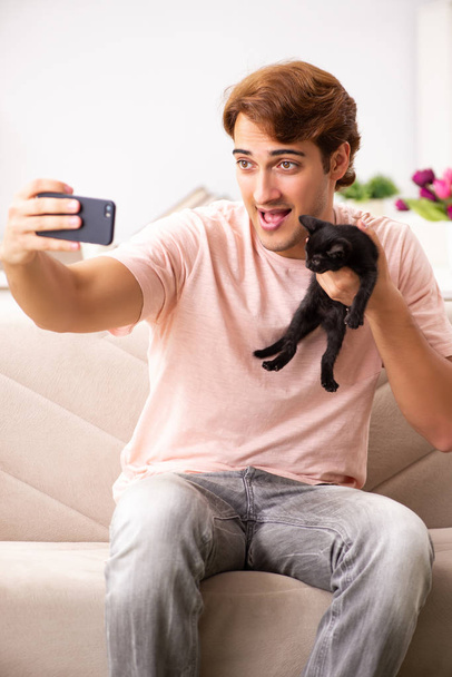 Jeune homme jouant avec chaton à la maison - Photo, image