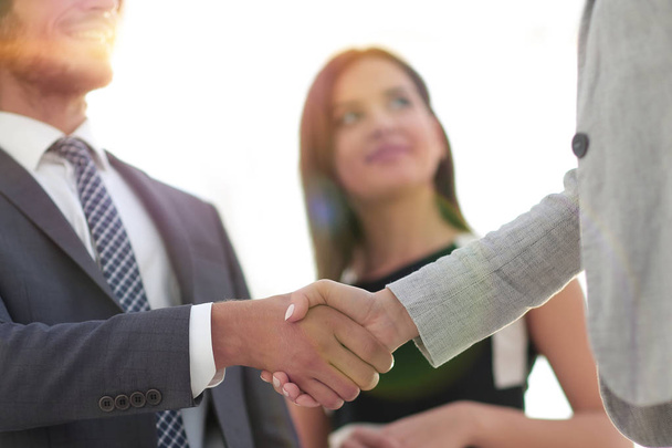 Business partners handshaking over business objects on workplace - 写真・画像
