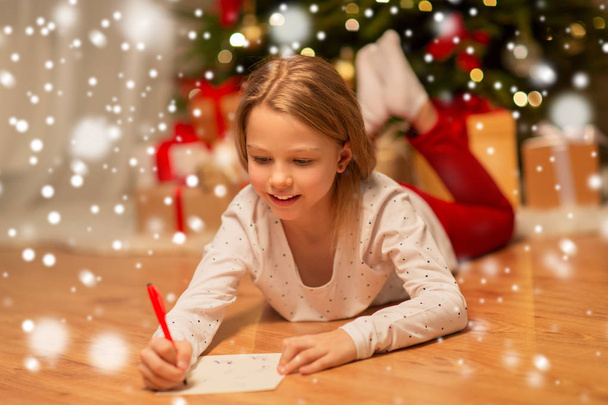 smiling girl writing christmas wish list at home - Foto, Imagem