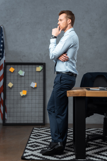 side view of pensive young businessman standing in modern office  - Photo, image