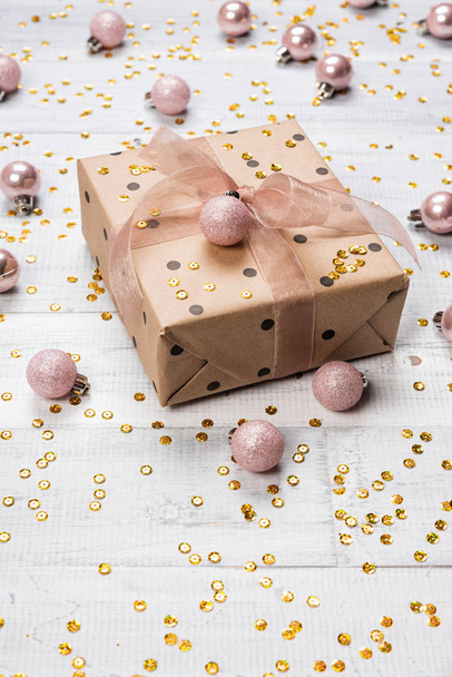 Weihnachtsgeschenke und Geschenkschachteln in Kraftpapier eingewickelt auf einem Holztisch mit Goldglitzern und rosa Kugeln, Tannenzweigen und Dekoration, Draufsicht. flache Lage, Kopierraum für Text. - Foto, Bild