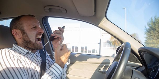 Небезпечний чоловік водить машину і кричить на мобільний телефон
  - Фото, зображення