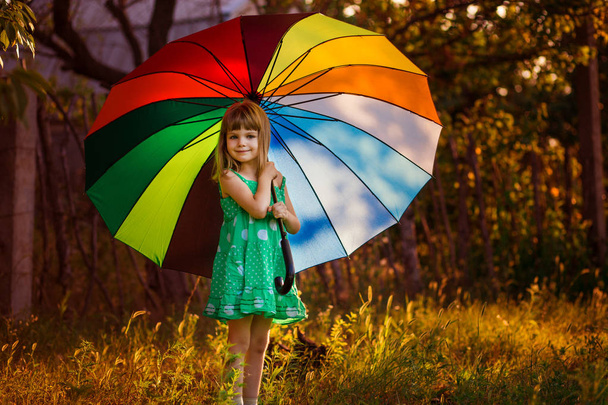 Feliz niña caminar con paraguas multicolor bajo la lluvia de otoño
  - Foto, Imagen