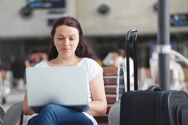 woman with laptop in airport, using internet connection, traveler checking email - Foto, immagini