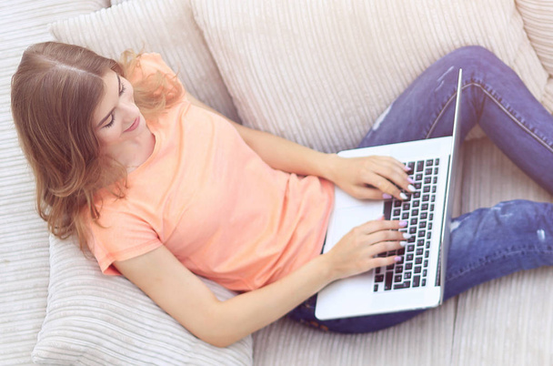 girl student working with laptop laying on the couch. - Фото, зображення
