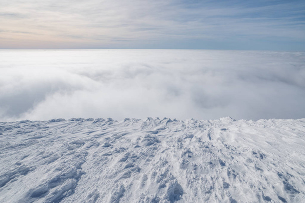 Mountain tops covered with snow above the white heavy clouds. - Foto, Imagen
