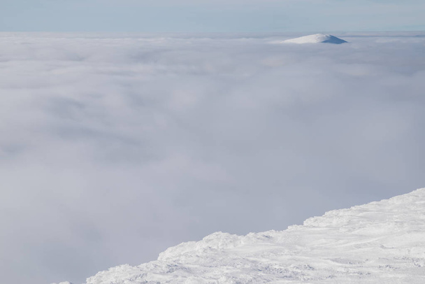 白の重い雲の上の雪で覆われた山の頂上. - 写真・画像