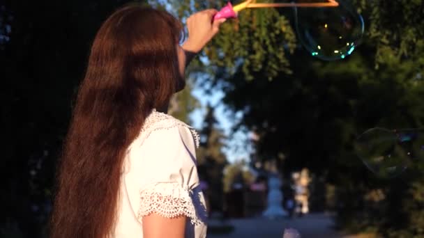 ευτυχισμένος κορίτσι λανσάρει μεγάλες σαπουνόφουσκες στο πάρκο της πόλης και χαμόγελα. Αργή κίνηση. - Πλάνα, βίντεο