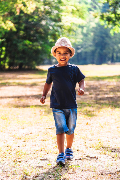 Close up portrait of little boy running outdoors in park - Foto, Imagen