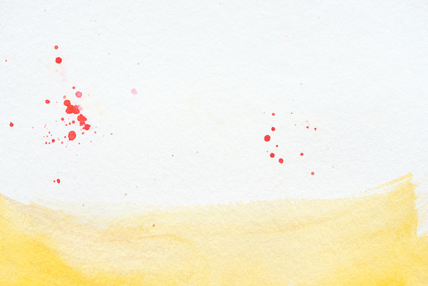 yellow watercolor stroke with red splatters on white paper background - Fotó, kép