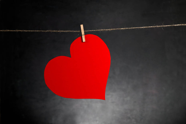 Sv. Fondo de San Valentín. Corazón rojo colgando de la cuerda sobre fondo oscuro con espacio para copiar
. - Foto, imagen