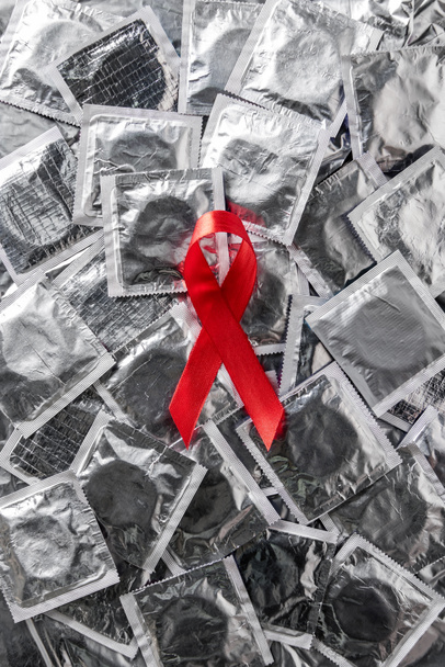 top view of aids awareness red ribbon on silver condoms  - Фото, зображення