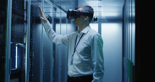 Técnico trabalha em um data center usando um fone de ouvido VR
 - Foto, Imagem
