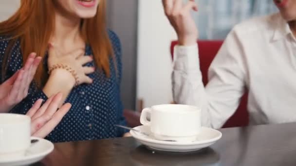 Friends met at the bar. Three young smiling women sitting in a cafe and talking. A girl put sugar in the tea. Close up - Video